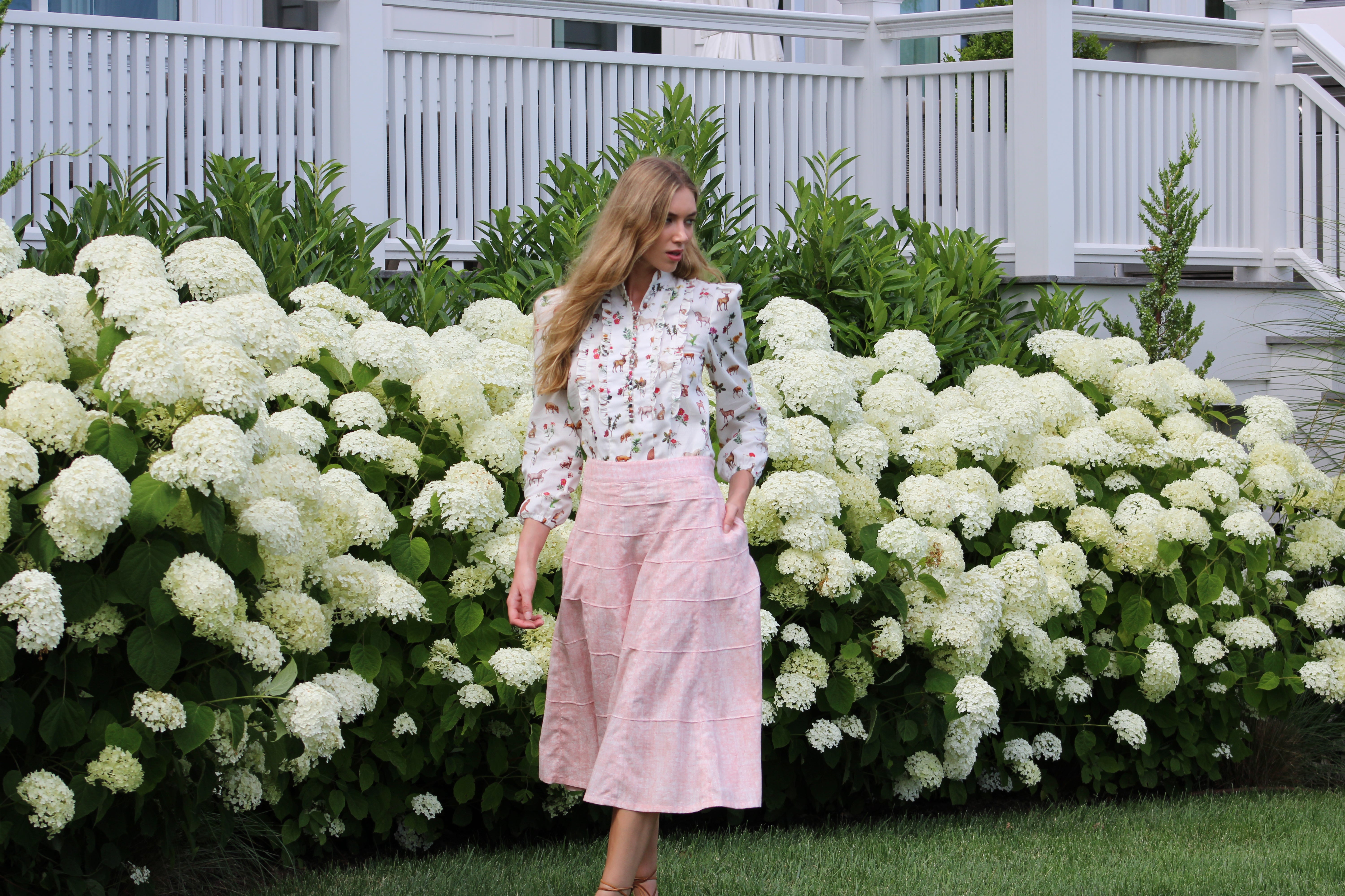 Woman standing in front of white hydrangeas and greenery